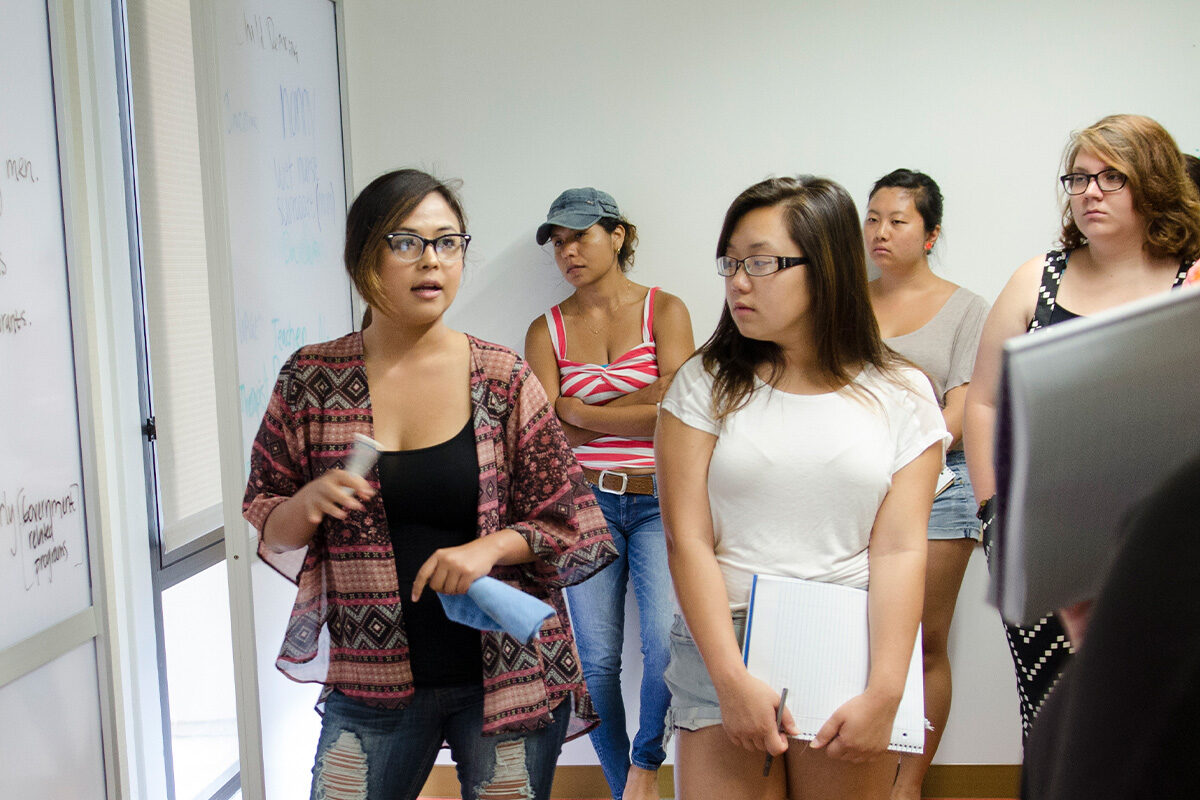 people looking at whiteboard while on person speaks